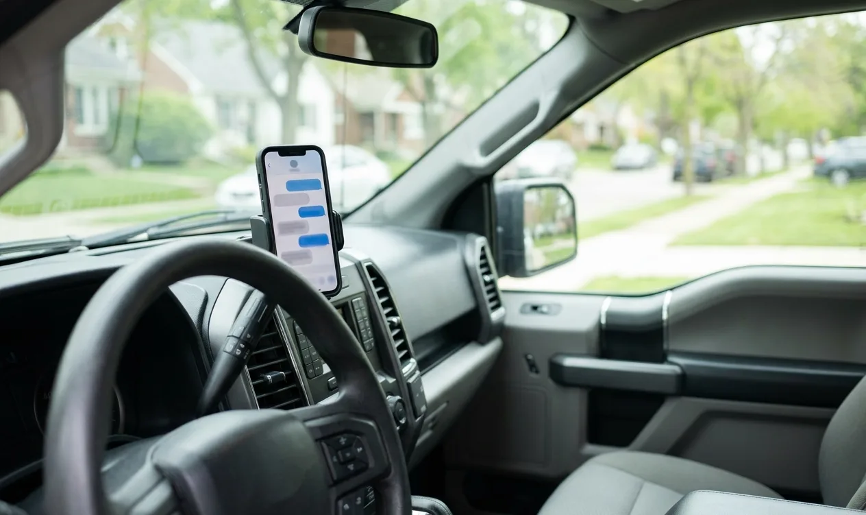Smartphone in a dashboard mount inside a parked work truck showing a message thread